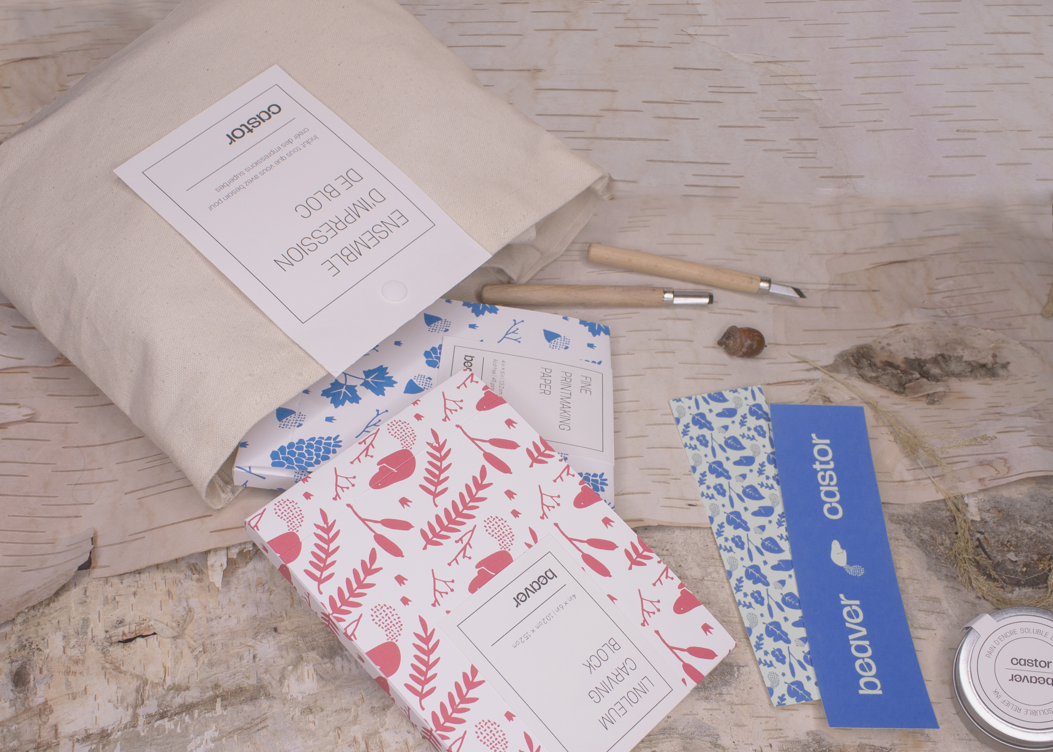 A spotlight photograph of the packaging for the Beaver block printing kit, showing two boxes and two carving knifes coming out of a canvas bag