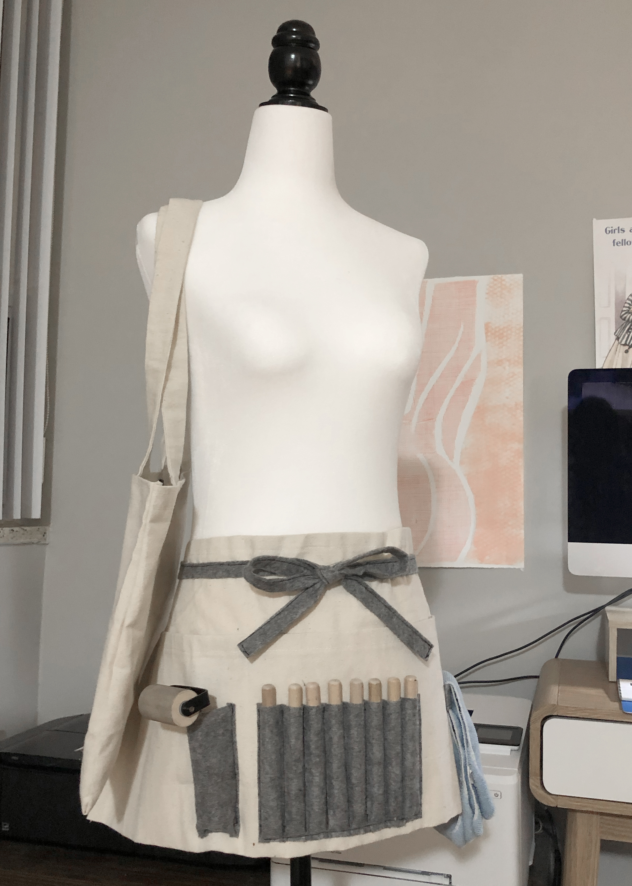 A photo of the canvas bag and half apron displayed on a dress form from head on